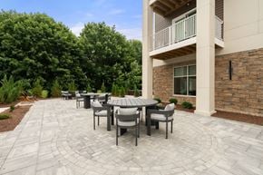 Somerset apartment for rent - A patio with a table and chairs is surrounded by a stone wall and trees.