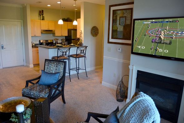 Lynnfield apartment for rent - A living room with a fireplace and a television showing a football game.