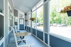 Taunton apartment for rent - A white rocking chair is on a porch with a table and a hanging flower basket.
