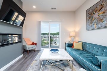 Canton apartment for rent - a living room with a blue couch and a fireplace    and a balcony