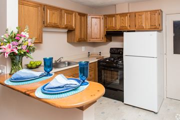 Ayer apartment for rent - A kitchen with wooden cabinets and a white refrigerator.