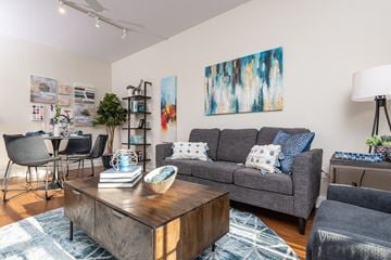 Chelsea apartment for rent - A living room with a grey couch, a wooden coffee table, and a painting on the wall.