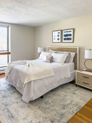 Quincy apartment for rent - A bedroom with a large bed and a blue patterned rug.