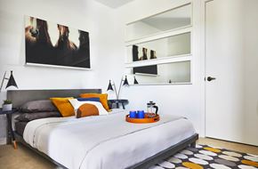 Jamaica Plain apartment for rent - A bedroom with a bed, a nightstand with a tray on it, and a painting on the wall, model apartment