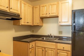 Taunton apartment for rent - A kitchen with wooden cabinets and a black refrigerator.