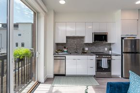 Somerville apartment for rent - a kitchen with white cabinets and stainless steel appliances and a sliding glass door that leads to a at Union 346 Apartments, Massachusetts, 02143
