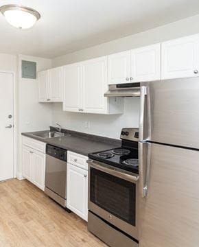 Dorchester apartment for rent - A kitchen with white cabinets and a black fridge.