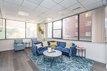 Boston apartment for rent - a living room with blue couches and a coffee table in front of a window