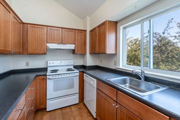 Nahant apartment for rent - A kitchen with wooden cabinets and a white stove top oven.