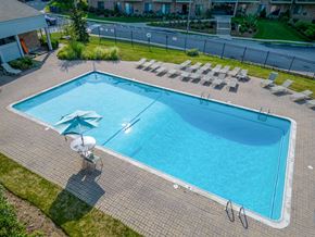 Quincy apartment for rent - an aerial view of a large swimming pool with lounge chairs and an umbrella