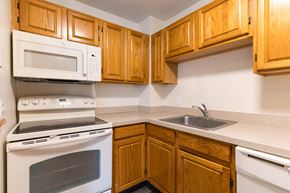 Lowell apartment for rent - A kitchen with wooden cabinets and a white oven.