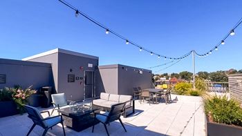 A patio with chairs and tables and lights on a roof