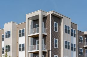 Somerset apartment for rent - Detail of building façade showing stacked private balconies, taupe siding and vertical columns against a clear blue sky.