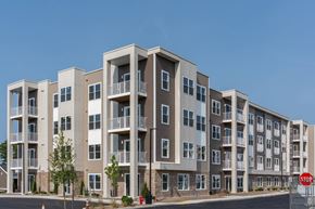 Somerset apartment for rent - Four-story apartment building at Slade Farm Residences with mixed tan siding, stone base accents and multiple balconies.