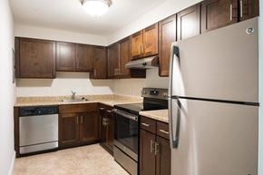 Weymouth apartment for rent - a kitchen with dark wood cabinets and stainless steel appliances