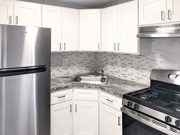 Lowell apartment for rent - A kitchen with white cabinets and a stainless steel refrigerator.