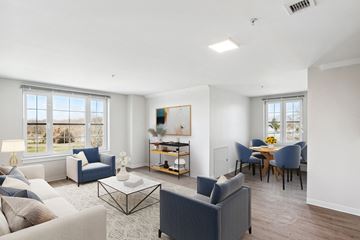 Branford apartment for rent - A living room with a grey sofa, a white armchair, a black coffee table, and a dining table with chairs.