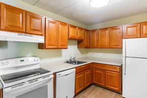 Framingham apartment for rent - A kitchen with white appliances and wooden cabinets at Edmands House, Massachusetts, 01701