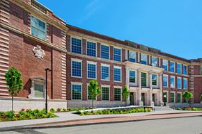 Beverly apartment for rent - a large brick building with many windows and a street in front at Beverly Village for Living & the Arts Apartments, Beverly, 01915