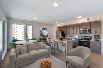 A modern living room with a couch, chair, and a kitchen area in the background