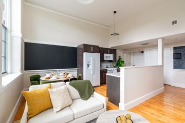 Beverly apartment for rent - A modern living room with a white couch and a dining table with chairs.