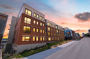 Pittsburgh apartment for rent - A modern building with a long row of windows is illuminated by the setting sun.