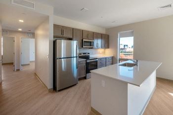 A kitchen with a refrigerator, microwave, oven, and sink