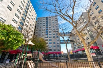 Boston apartment for rent - A playground with a slide and a tree in front of apartment buildings.