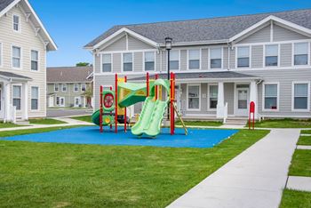 A playground with a blue mat in front of a building