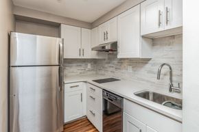 Pittsburgh apartment for rent - Kitchen Layout With White Cabinets And Stainless Steel Appliances. Living Room and Dining Room Layout With Window And Tables And Chairs, Highland Plaza Apartments, Pittsburgh, PA.