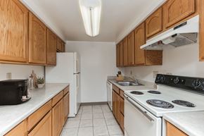 Pittsburgh apartment for rent - a kitchen with white appliances and wooden cabinets at Bates Hill Apartments Pittsburgh, PA.