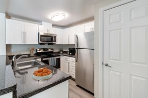 Littleton apartment for rent - A kitchen with a sink, microwave, oven, and refrigerator A kitchen with wooden cabinets and stainless steel appliances at Pondside at Littleton Apartments in Littleton, MA, 01460