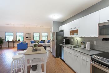 A kitchen and living room with white cabinets and a table and chairs