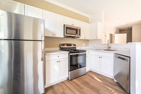 Abington apartment for rent - a kitchen with white cabinets and stainless steel appliances at Woodlands at Abington Station, Abington, MA, 02351