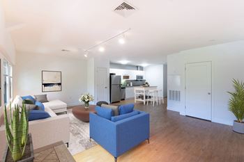 A living room with couches and a table with a kitchen in the background
