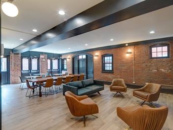 A lounge area with chairs and tables and a brick wall