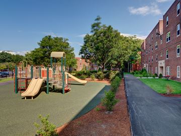 Boston apartment for rent - a playground with slides in front of a brick building