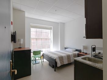 A bedroom with a bed and a sink and a chair