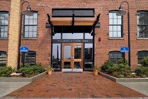 Haverhill apartment for rent - The entrance to a brick building with a wooden overhang and a sign that reads at The Cordovan at Haverhill Station, Haverhill, MA
