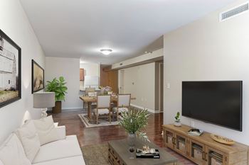A living room with a large tv on the wall and a dining room table in the background