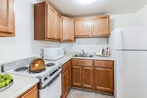 Wheeling apartment for rent - a kitchen with white appliances and wooden cabinets at Montani Towers, Wheeling West Virginia