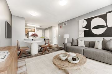 Buffalo apartment for rent - A modern living room with a grey couch, a wooden coffee table, and a large abstract painting on the wall.