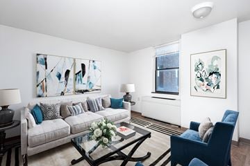 Erie apartment for rent - A living room with a grey couch, a coffee table, and two paintings on the wall.