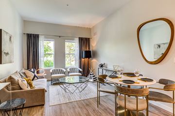 Amherst apartment for rent - A modern living room with a glass coffee table and a round mirror on the wall.