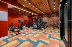 Haverhill apartment for rent - A gym with a variety of exercise equipment and a colorful floor at The Cordovan at Haverhill Station, Haverhill, MA