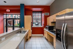 Haverhill apartment for rent - A kitchen with a red wall and a stainless steel refrigerator at The Cordovan at Haverhill Station, Haverhill, MA