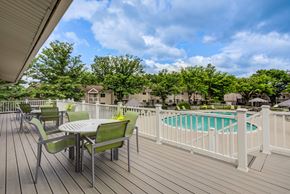 Harrisburg apartment for rent - A wooden deck with a table and chairs overlooking a pool at Williamsburg Estates, Harrisburg, PA, 17112
