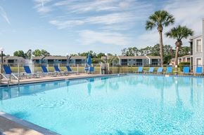 Ormond Beach apartment for rent - A large swimming pool with blue water and lounge chairs Fishermans Landing Apartments in Ormond Beach, FL.