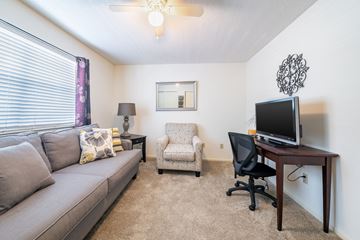 Ormond Beach apartment for rent - A living room with a grey couch, a chair, a table with a computer monitor and a lamp.