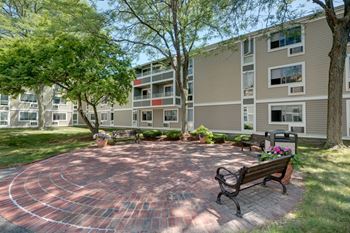 A circular brick patio with benches in front of an apartment building